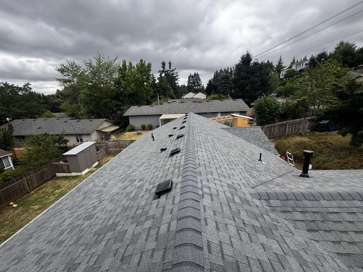 New shingle roof ridge view under dramatic clouds by Mistletoe Construction, Douglas County Oregon